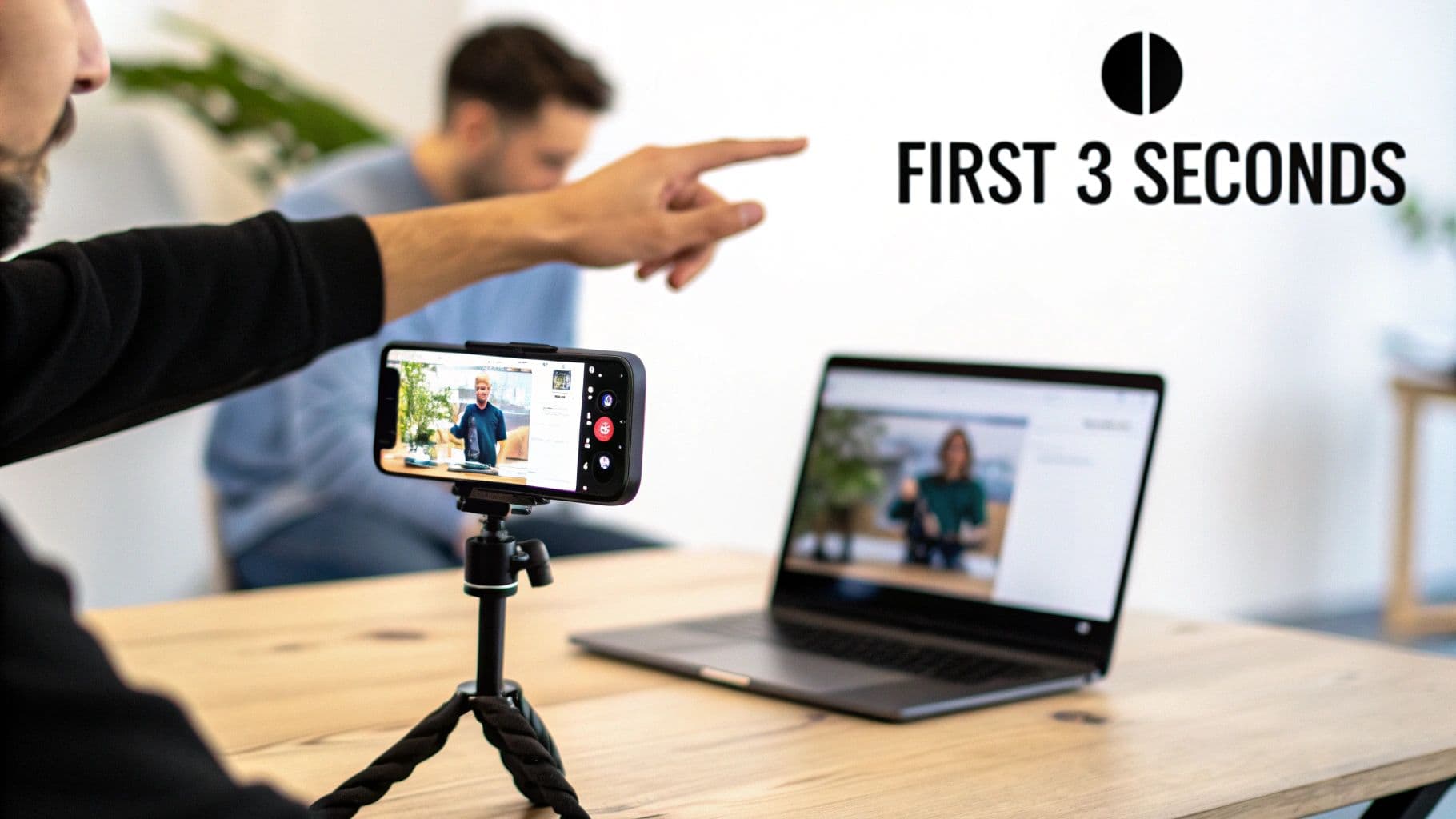 Man filming video with smartphone on tripod, laptop displaying content, with 'FIRST 3 SECONDS' text on wall.